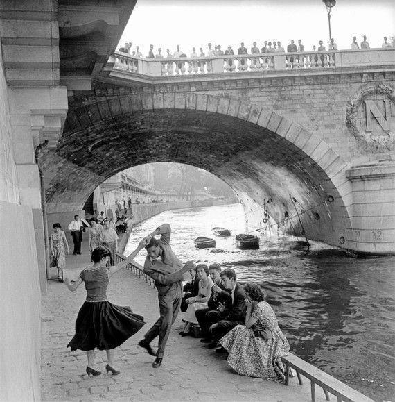 11. A Couple Dances Along the Seine as People Look on 1. A Woman Strolls Through Paris While Reading the Paper, 2. Two Kids Play With a Toy Car on a Cobblestone Street With the Moulin Rouge in the Distance, 3. ‘A Pair of Lovers in Paris, France’, 4. Visitors Stroll Beneath the Eiffel Tower During the 1925 Exposition Internationale des Arts Décoratifs, 5. Colorized Image of Parisians Browsing Flowers Near the Tour de l’Horloge on the Île de la Cité, One of the City’s Oldest Clocks, 6. ‘Soldiers at the Metro Station Auteuil on the Boulevard Excelmans in Paris, France, on May 1, 1920’, 7. Colorized Image of a Hot Air Balloon Pre-Take Off, May 1923, 8. Two Women Enjoy a Coffee on a Terrace, 1925, 9. ‘A Street Scene in Paris During the 1924 Olympics’, 10. A Woman Enjoys a Meal Aboard a Zeppelin Heading to Berlin, 1928, 11. A Couple Dances Along the Seine as People Look on, 12. Singer and Dancer Josephine Baker Pictured at a Cabaret, 1927, 13. Three Children Pause for a Snack With the Sacré-Coeur in the Distance, 14. ‘Ernest Hemingway in Paris, 1920s’, 15. ‘Citroen Automobile Designed by Sonia Delaunay in Paris, 1925’, 16. A Young Gloria Vanderbilt and Her Pet Dog Playing in Front of the Eiffel Tower, 1921, 17. ‘Backstage at the Moulin Rouge, Paris, 1924’, 18. ‘Early Color Photography in Paris, France, 1920’, 19. Josephine Baker Taking Her Pet Cheetah for a Walk in Paris, 1923