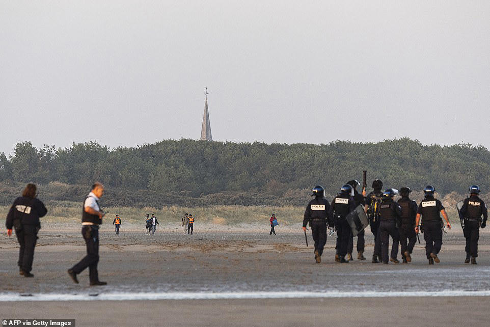 French police stand watching as boat load of migrants set off for UK