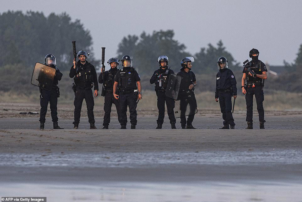 French police stand watching as boat load of migrants set off for UK