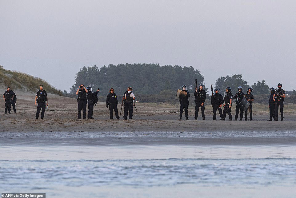 French police stand watching as boat load of migrants set off for UK