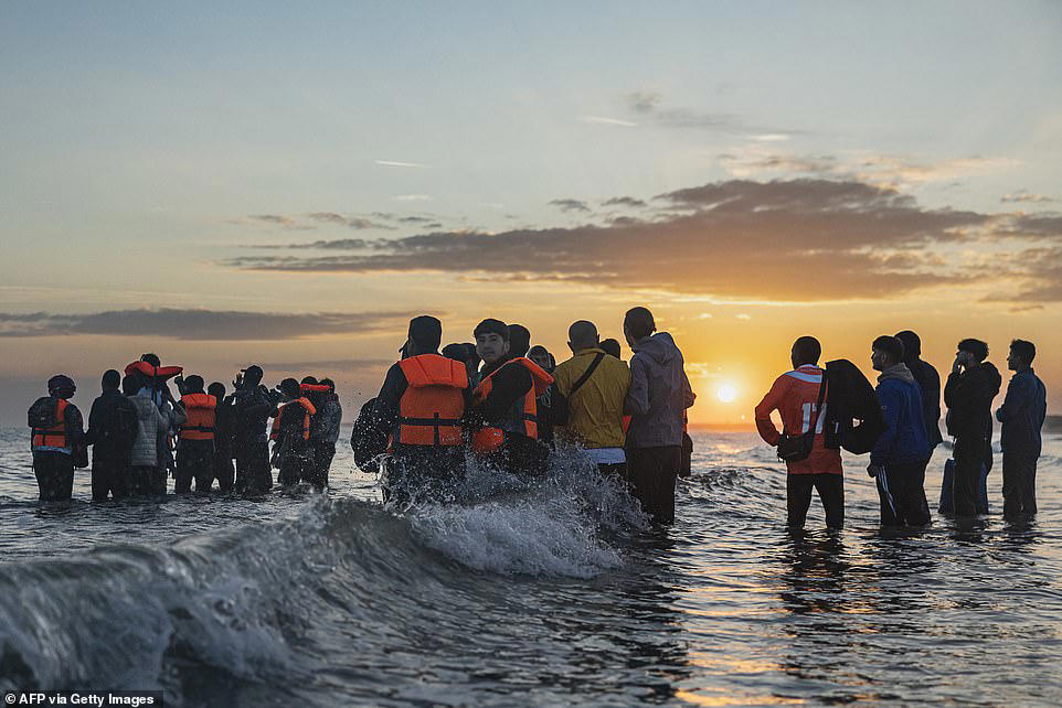French police stand watching as boat load of migrants set off for UK