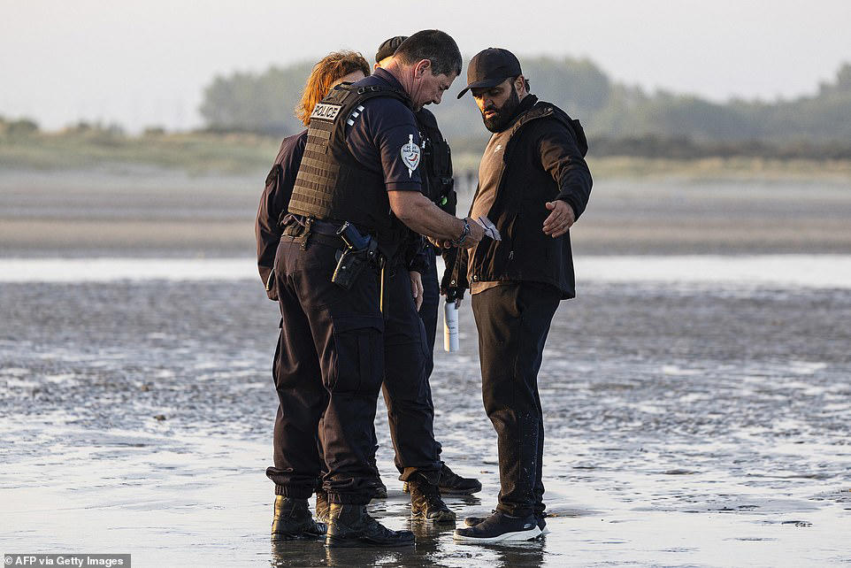 French police stand watching as boat load of migrants set off for UK