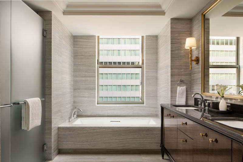 The bathrooms feature luxurious amenities like heated marble tile floors, walk-in showers, and separate dressing areas.