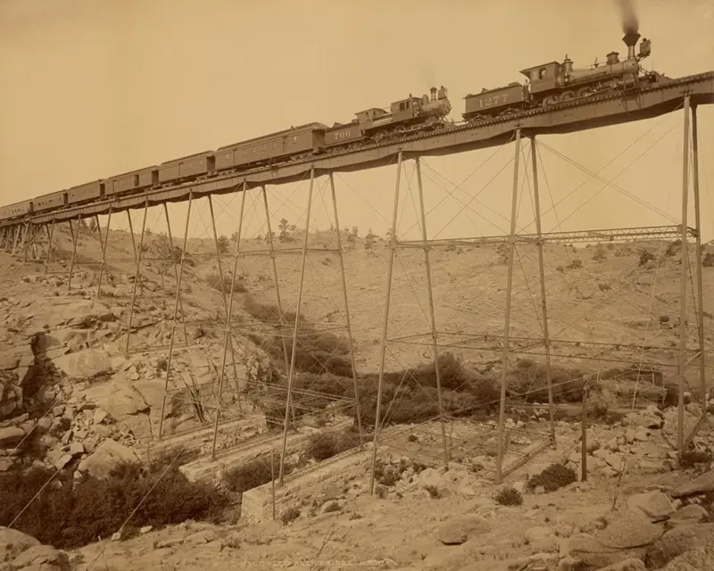 14. Would you trust this bridge on the Central Pacific side of the Transcontinental Railroad? 1. The day the Transcontinental Railroad was officially completed in Colorado, August 15, 1870, 2. A Native American looking down on the newly completed section of the Transcontinental Railroad, 3. Celebrating the completion of the Transcontinental Railroad in Promontory Point, Utah, 1869, 4. Hopping on the handcar to get to work on the Transcontinental Railroad, 1860s, 5. All hands on deck, 1864, 6. Laborers laid an average of ten miles of track per day, 7. The Dale Creek Crossing, a wooden railroad, under construction during the building of the Transcontinental Railroad, 1868, 8. Heading to the tracks to witness the completion of the railroad, 1870, 9. The Jupiter train, which was one of the first locomotives on the Transcontinental Railroad, 1860s, 10. Workers had to cut through 1,000 miles of trees through the narrows of Weber Canyon, 1869, 11. Checking to see if there would be any rock slides onto the railroad, 12. The Central Pacific First Transcontinental Railroad, built from Sacramento, California, to Summit, Utah in 1865, 13. A railroad camp near Victory, 1869, 14. Would you trust this bridge on the Central Pacific side of the Transcontinental Railroad?, 15. Imagine all of the work that went into digging through that mountain