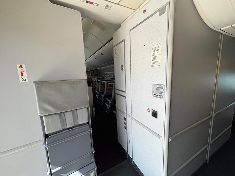 I knew the crew rest area would be at the back of the plane, but it was still quite hidden. The door opens to reveal a steep and narrow staircase., It was slightly eerie looking down the dim and lengthy corridor., However, the beds themselves didn't look too uncomfortable., Each bed had pockets for storage, a coat hook, and a mirror.