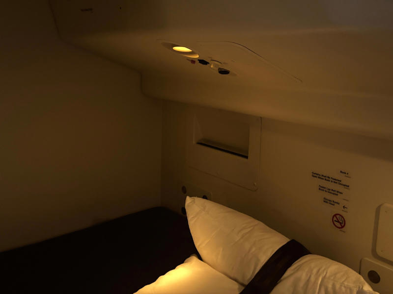 Plus, they had light and air flow controls, similar to a seat in the cabin. The door opens to reveal a steep and narrow staircase., It was slightly eerie looking down the dim and lengthy corridor., However, the beds themselves didn't look too uncomfortable., Each bed had pockets for storage, a coat hook, and a mirror.