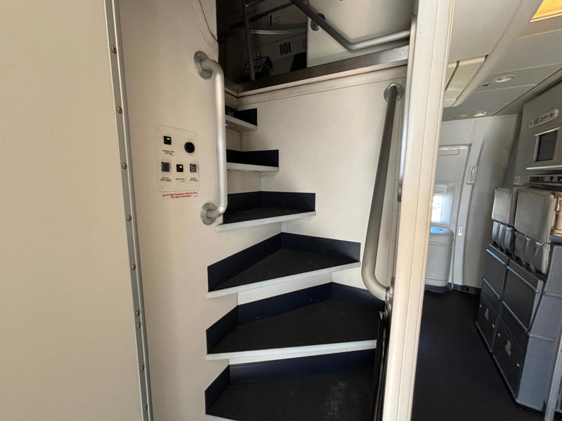 The door opens to reveal a steep and narrow staircase. The door opens to reveal a steep and narrow staircase., It was slightly eerie looking down the dim and lengthy corridor., However, the beds themselves didn't look too uncomfortable., Each bed had pockets for storage, a coat hook, and a mirror.