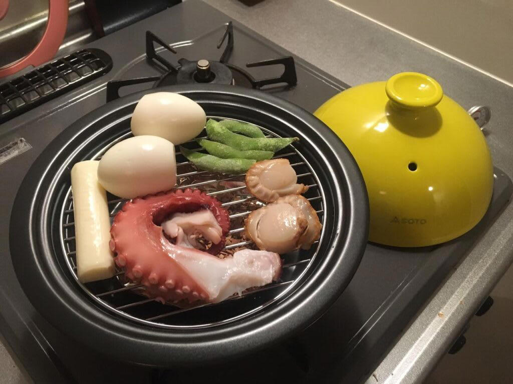 燻製の3つの工程, 1.味付け（塩漬け）, まずはコレから！ 燻製におすすめの「定番」食材10選, 1.とろーり半熟が絶品！ 燻製たまご, 2.下ごしらえ不要で簡単！ 燻製チーズ, 3.パリッとジューシー！ 旨味があふれる燻製ソーセージ, 4.焼くより香ばしい？ 新しい発見、燻製ししゃも, 5.いつものナッツが高級おつまみに！ ウイスキーと楽しむ燻製ナッツ, 6.旨味をギュッと凝縮！ 半生食感がたまらない燻製ほたて, 7.キャンプ飯の王様！ 厚切りブロックで味わう豪快燻製ベーコン, 8.冷蔵庫のちくわがごちそうに！ 超簡単・節約おつまみ燻製, 9.まるで「いぶりがっこ」！ 市販のたくあんで作る絶品燻製, 10.罪悪感なしの絶品おつまみ！ 高タンパク・低カロリー燻製ささみ, 燻製の世界が広がる！ おすすめの「変わり種」食材8選, 1.いつもの卵かけご飯が絶品に！ 魔法の調味料「燻製醤油」, 2.明太子が高級珍味に！ 旨味を凝縮した燻製おつまみ, 3.まさかのマヨネーズも燻製に？ ディップソースの新革命！, 4.わずか5分で完成！ 市販のポップコーンで作る、やみつき燻製スナック, 5.のり塩、コンソメが狙い目！ 味付きで楽しむ燻製ポテトチップス, 6.キャンプの夜の決定版！ アイスを乗せたい「とろける燻製バナナ」, 7.焼き、蒸し、揚げに続く！ 「燻す」という第4の餃子、現る, 8.夏の定番が劇的進化！ ビールが止まらなくなる「燻製枝豆」, 燻製に必要なアイテム, ダンボールやフライパンでもOK！燻製器なしで作る方法, ダンボールでの燻製方法, フライパンでの燻製方法, 本格的に楽しみたい方におすすめの燻製器, 燻製器選びの3つのポイント, おすすめ燻製器【1】ドウシシャ クッカーブラック直径12cm, おすすめ燻製器【2】SOTO（ソト）「燻家（スモークハウス）」, おすすめ燻製器【3】サーモス「保温燻製器 イージースモーカー」, おすすめ燻製器【4】キャプテンスタッグ（CAPTAIN STAG）「アドバンス 折りたたみスモーカー」, 自分だけの燻製ライフを始めよう
