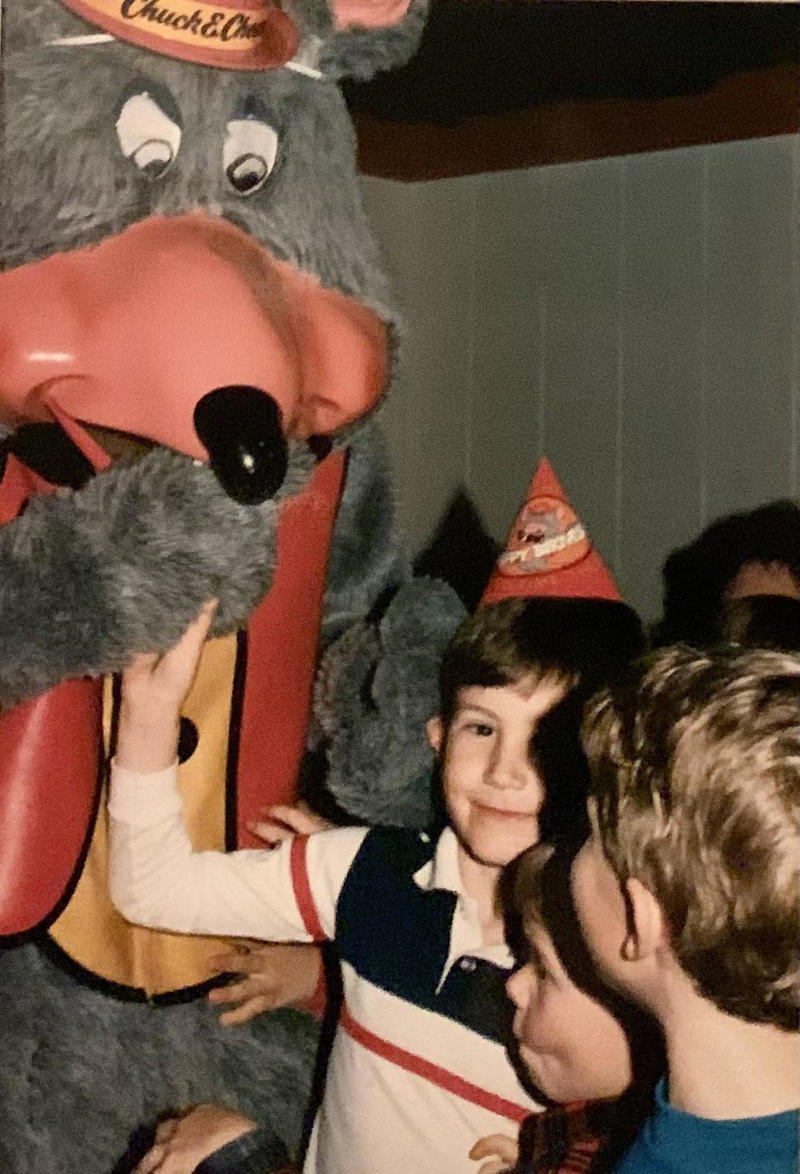 1. Core Memories in the Making, 2. Fresh Pizza Delivered By Chuck Himself? Talk About Birthday Goals, 2. ‘Looking Tough on My 6th Birthday at Chuck E. Cheese in 1996’, 4. Admittedly, Chuck Looked a Bit Creepy at Times, 5. Bet He Remembers the Rage to This Day: ‘The Exact Moment a Random Kid Blew Out My Candles at Chuck E. Cheese in 1991’, 6. A Crown Fit for a [Small] Queen, 7. ‘My Chuck E. Cheese Birthday Party, 1986’, 8. Enjoying Some Pizza While Watching the Animatronic Band, 9. ‘Birthday Party at the Very First Chuck E. Cheese in the Old Town and Country Village Shopping Center’, 10. ‘Fun Birthday Party at Chuck E. Cheese, Late ’80s’, 11. Grown Up Parties Welcome, Too!, 12. No Birthday Was Complete Before All the Gifts Were Opened, 13. You Don’t Say: ‘Me in 1987 With a Creepy-Looking Chuck E Cheese’, 14. ‘At Chuck E. Cheese Proudly Showing Off My Coins, 1993’, 15. ‘Me at Chuck E. Cheese on My 5th Birthday, July 1982’