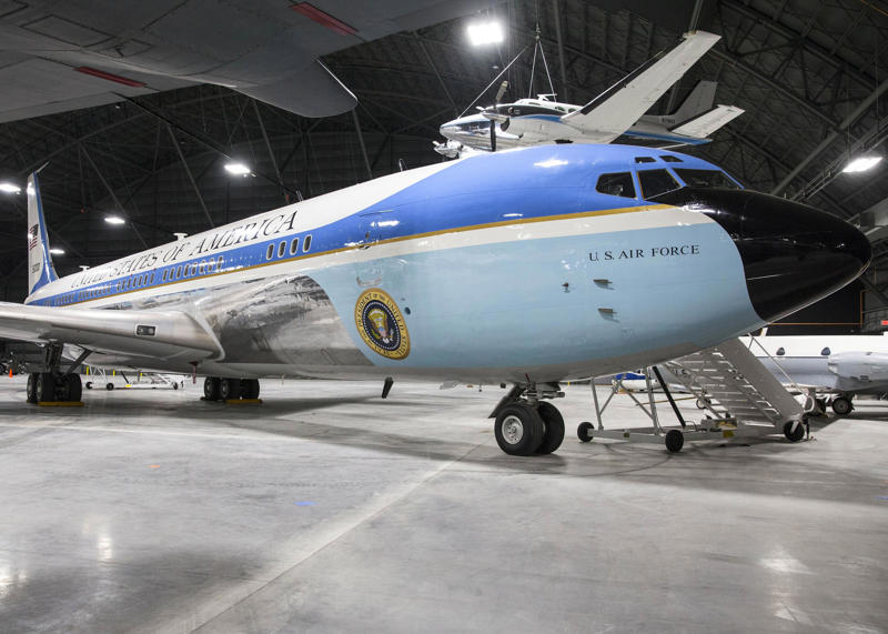The SAM 26000 Air Force One jet, a Boeing VC-137C, was completed in 1962 for President John F. Kennedy. Two phones were located behind the flight deck., An equipment storage space featured a first aid kit and firearms., Next, I walked by the plane's communication facility., Meals were prepared in the galley., The presidential stateroom was located down a long hallway., The president's spacious quarters featured a desk, couch, television, and private bathroom., The stateroom came with two phones, each with different purposes., Behind the presidential stateroom, a conference room provided more meeting space.