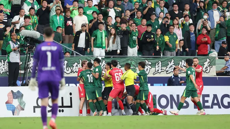 中国とベトナムのサッカー選手が乱闘。, AFCチャンピオンズリーグの試合中に混乱が発生。, 北京国安対ベトナム・ハノイ戦の終盤、乱闘が勃発した。, 両チームの選手が入り乱れての大乱闘。, 時間を無駄にしていた事から口論となり、さらには乱闘へと発展した。, 激しい殴打で状況は緊迫した。, 審判は落ち着きを取り戻そうと奮闘した。, 試合は6分以上中断された。, スタンドから観客がピッチにボトルを投げ入れて抗議した。, 看板の上に倒れる選手もいた。, 意外なことに、審判は誰も退場させなかった。, 緊迫したこの試合は2-2で終了した。