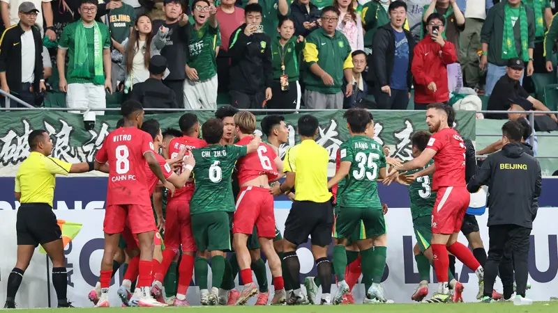 中国とベトナムのサッカー選手が乱闘。, AFCチャンピオンズリーグの試合中に混乱が発生。, 北京国安対ベトナム・ハノイ戦の終盤、乱闘が勃発した。, 両チームの選手が入り乱れての大乱闘。, 時間を無駄にしていた事から口論となり、さらには乱闘へと発展した。, 激しい殴打で状況は緊迫した。, 審判は落ち着きを取り戻そうと奮闘した。, 試合は6分以上中断された。, スタンドから観客がピッチにボトルを投げ入れて抗議した。, 看板の上に倒れる選手もいた。, 意外なことに、審判は誰も退場させなかった。, 緊迫したこの試合は2-2で終了した。