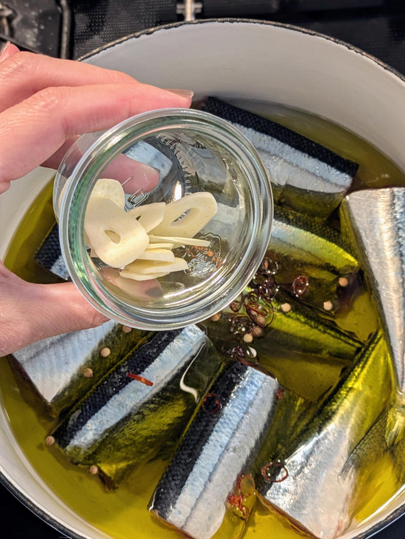秋刀魚と身近な材料で作れるコンフィ, 鍋にオーブンペーパーを敷いて、焦げ防止, オーブンペーパーで落とし蓋をして低温で煮る, オイルごと密閉で1週間保存可能, 盛りつけるだけで一品完成, 夜のワインのお供に！秋刀魚コンフィでバゲットサンド, 秋刀魚コンフィパスタで、おとなの夜ごはん