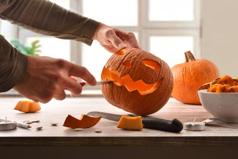 Step 1. Start with the right pumpkin. , Step 2. Begin cutting from the bottom, not the top. , Step 4. Scoop out all the pulp (and then some). , Step 5. Sketch out the design on paper first., Step 6. Hold the pumpkin in your lap. , Step 7. Start with simple rough cuts. , Step 8. Use scraps creatively., Step 9. Keep your pumpkin fresh. , Step 10. Light it up. , Step 11. Create a chimney. , Step 12. Sprinkle cinnamon inside the lid. 