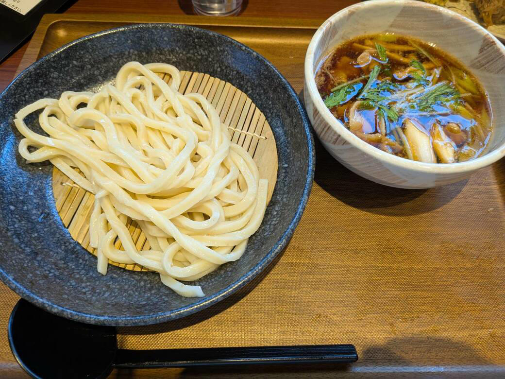 猫も杓子も体験…やたら「体験」を推す外食企業, 新業態1号店は堅実に郊外ロードサイド, オープンから半月経過も行列ができる人気ぶり, 注文はタブレット、上げ膳・下げ膳まですべてお客がやる, 1000円前後で食べ放題付きはお得, 「豚肉つけ汁うどん」1089円はこんな感じ, 従来のうどんチェーンは注文に高度な意思決定が求められる？, 意思決定が負担、でも失敗したくない…現代人のニーズに合ううどん店