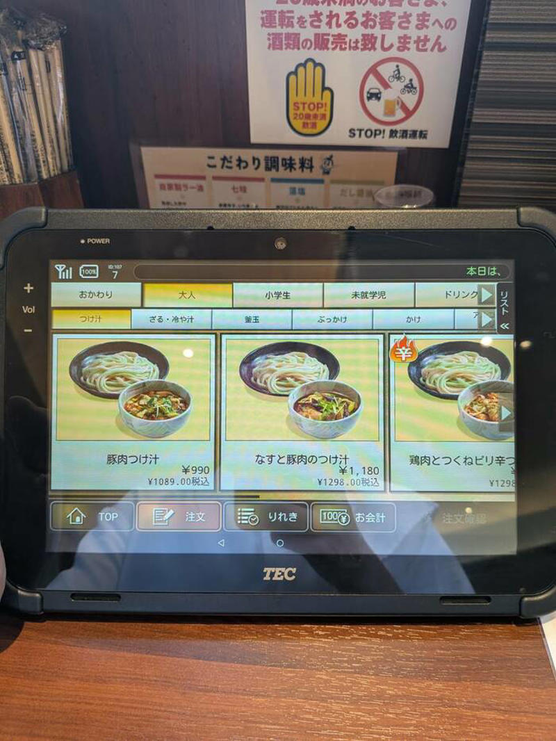 猫も杓子も体験…やたら「体験」を推す外食企業, 新業態1号店は堅実に郊外ロードサイド, オープンから半月経過も行列ができる人気ぶり, 注文はタブレット、上げ膳・下げ膳まですべてお客がやる, 1000円前後で食べ放題付きはお得, 「豚肉つけ汁うどん」1089円はこんな感じ, 従来のうどんチェーンは注文に高度な意思決定が求められる？, 意思決定が負担、でも失敗したくない…現代人のニーズに合ううどん店
