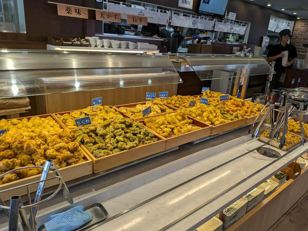 猫も杓子も体験…やたら「体験」を推す外食企業, 新業態1号店は堅実に郊外ロードサイド, オープンから半月経過も行列ができる人気ぶり, 注文はタブレット、上げ膳・下げ膳まですべてお客がやる, 1000円前後で食べ放題付きはお得, 「豚肉つけ汁うどん」1089円はこんな感じ, 従来のうどんチェーンは注文に高度な意思決定が求められる？, 意思決定が負担、でも失敗したくない…現代人のニーズに合ううどん店