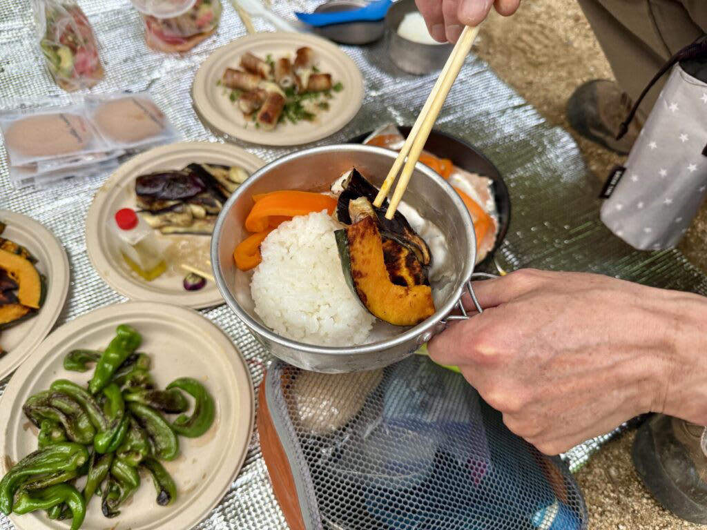 キャンプでご飯を炊く前に！まずは基本の道具を知ろう, 炊飯に必要な「基本セット」, 道具のメリット・デメリット, キャンプで失敗せずに美味しくご飯を炊くコツ, 1.米と水の「計量」は正確に行う, 2.「吸水」を最低30分（冬場は1時間）は行う, 3.火加減は「沸騰するまで中火 → 沸騰したら弱火」, 4.炊飯中は「絶対に蓋を開けない」, 5.火から下ろしたら「必ず10分以上蒸らす」, 【道具別】炊き方ガイド｜メスティン・飯ごう・鍋・ライスクッカー・ダッチオーブン, 鍋（クッカー）は重しを使うのがポイント, 飯ごうは蓋で軽量もできるのがポイント, メスティンは火加減がポイント, ライスクッカーは機能をフル活用するのがポイント, ダッチオーブンは蓋の上に炭を置くのがポイント, もっと美味しく！キャンプで食べたい絶品ご飯レシピ, 缶詰ひとつで味が決まる！超簡単「炊き込みご飯」, 「お焦げ」も「残りご飯」もごちそうに！翌朝活用レシピ, 美味しいご飯が、キャンプをもっと楽しくする