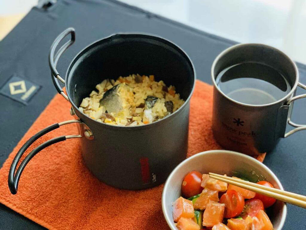 キャンプでご飯を炊く前に！まずは基本の道具を知ろう, 炊飯に必要な「基本セット」, 道具のメリット・デメリット, キャンプで失敗せずに美味しくご飯を炊くコツ, 1.米と水の「計量」は正確に行う, 2.「吸水」を最低30分（冬場は1時間）は行う, 3.火加減は「沸騰するまで中火 → 沸騰したら弱火」, 4.炊飯中は「絶対に蓋を開けない」, 5.火から下ろしたら「必ず10分以上蒸らす」, 【道具別】炊き方ガイド｜メスティン・飯ごう・鍋・ライスクッカー・ダッチオーブン, 鍋（クッカー）は重しを使うのがポイント, 飯ごうは蓋で軽量もできるのがポイント, メスティンは火加減がポイント, ライスクッカーは機能をフル活用するのがポイント, ダッチオーブンは蓋の上に炭を置くのがポイント, もっと美味しく！キャンプで食べたい絶品ご飯レシピ, 缶詰ひとつで味が決まる！超簡単「炊き込みご飯」, 「お焦げ」も「残りご飯」もごちそうに！翌朝活用レシピ, 美味しいご飯が、キャンプをもっと楽しくする