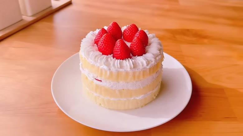 ①.   クッキングシートをタッパーの側面に合わせてカット, ②.   クッキングシートをタッパーの底面に合わせてカット, ①.　耐熱ボウルにスーパーカップを入れ電子レンジで溶かす, ②.　①に砂糖、油を加えて混ぜる, ③.　②にホットケーキミックスを加えて混ぜる, ④.　③の生地をタッパーに流し入れ、何回かトントン落としてふんわりラップをかける, ⑤.　電子レンジで加熱する, ⑥.　キッチンペーパーをかぶせて網で冷ます, ⑦.　クッキングシートを外してスポンジを3枚にカットする, ⑧.　シロップを染み込ませながらデコレーションする, ⑨.　最後に1時間ほど冷蔵庫で冷やして完成