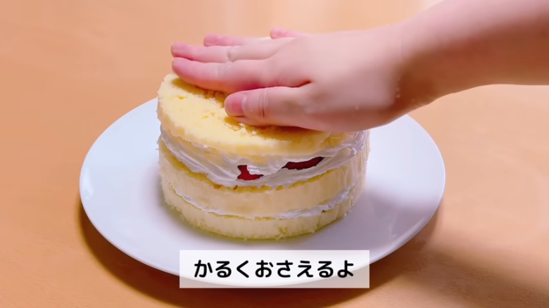 ①.   クッキングシートをタッパーの側面に合わせてカット, ②.   クッキングシートをタッパーの底面に合わせてカット, ①.　耐熱ボウルにスーパーカップを入れ電子レンジで溶かす, ②.　①に砂糖、油を加えて混ぜる, ③.　②にホットケーキミックスを加えて混ぜる, ④.　③の生地をタッパーに流し入れ、何回かトントン落としてふんわりラップをかける, ⑤.　電子レンジで加熱する, ⑥.　キッチンペーパーをかぶせて網で冷ます, ⑦.　クッキングシートを外してスポンジを3枚にカットする, ⑧.　シロップを染み込ませながらデコレーションする, ⑨.　最後に1時間ほど冷蔵庫で冷やして完成