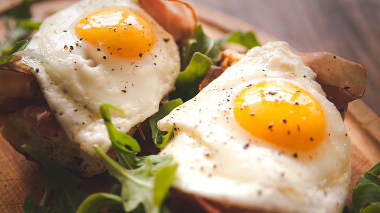 Use a hot, lubricated pan to prevent sticking, For lacy, crispy edges, baste the eggs' edges with hot oil, Add water for fried eggs with tender, uncolored whites, Add buttery, toasty richness by frying eggs in cream, Here's how to get firm whites while keeping the yolk runny, Use room temperature eggs to ensure even frying, Add a splash of vinegar for a simple twist, To add extra crunch and flavor, fry eggs on shredded Parmesan, Cooking for a crowd? Fry your eggs in the oven
