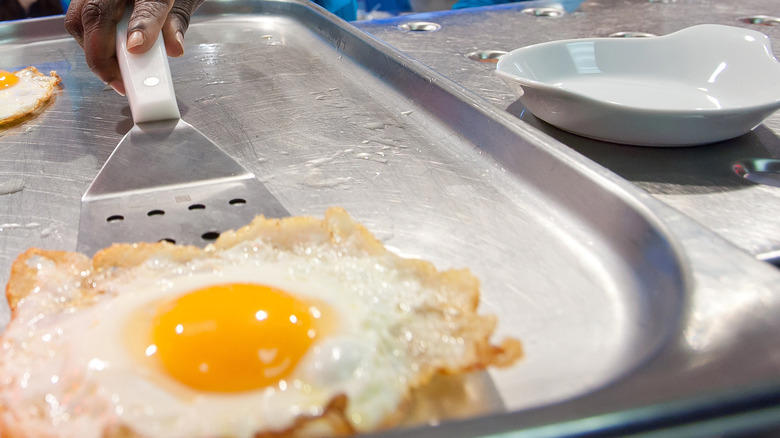 Use a hot, lubricated pan to prevent sticking, For lacy, crispy edges, baste the eggs' edges with hot oil, Add water for fried eggs with tender, uncolored whites, Add buttery, toasty richness by frying eggs in cream, Here's how to get firm whites while keeping the yolk runny, Use room temperature eggs to ensure even frying, Add a splash of vinegar for a simple twist, To add extra crunch and flavor, fry eggs on shredded Parmesan, Cooking for a crowd? Fry your eggs in the oven