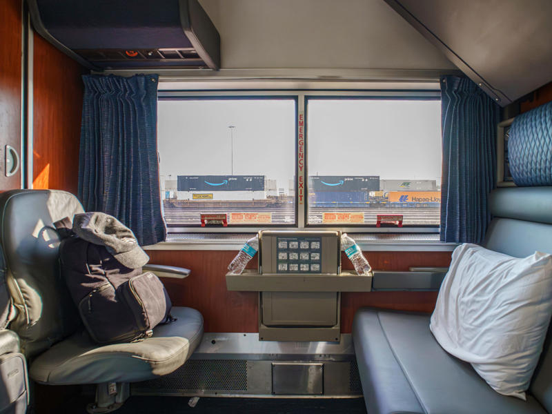 When I first boarded the train, there were no bunks in sight. When I first boarded the train, there were no bunks in sight., There was also a narrow closet at the front of the room., Across from the closet, there was a sink and vanity., I used the shelf above the single seat to store my luggage., I found room controls on either side of the couch., Among these controls was a night setting for the lights., I slept in the bottom bunk on the second night.