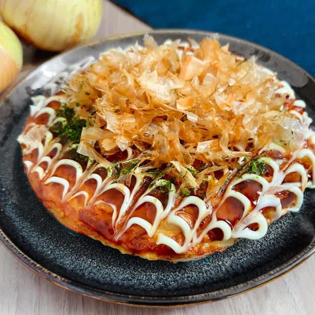 新玉ねぎと豆腐のふわふわ焼き, 作り方：①ボウルに絹豆腐を入れてなめらかになるまで混ぜる。, ② ①に【A】を入れて混ぜ、新玉ねぎを加えて混ぜる。, ③ フライパンにサラダ油を引いて弱めの中火に熱し、②を入れる。ふたをして３分程両面を焼き、お好み焼きソースを塗る。お好みのトッピングをしたら、完成！, 外はほんのりさくっと、中は想像以上にふわっふわ！！