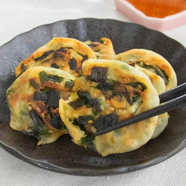 くるくるニラ焼き, 【ニラを買ったらコレにして】餃子の皮で作る！くるくるニラ焼き｜簡単節約おかず, ニラと玉ねぎのチヂミ, 【ニラを1束使い切り！】10分で完成！ニラと玉ねぎのおいしさが詰まったチヂミレシピ, 豆腐とニラの卵炒め, 【豆腐でコスパ抜群】節約したい時にもおすすめ！豆腐とニラの卵炒めレシピ