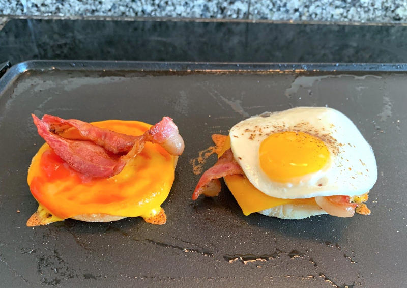 Marchand's bacon and egg muffin requires just a few main ingredients., To begin, I first cooked my bacon., As the bacon started cooking, I prepped my English muffins., Then it was time to start building the sandwich., Once the cheddar slices had softened, it was time for some saucin'., Then I added the bacon slices., I plopped my egg right on top of the bacon.