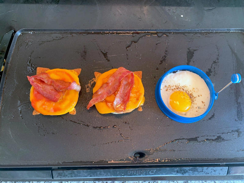 Marchand's bacon and egg muffin requires just a few main ingredients., To begin, I first cooked my bacon., As the bacon started cooking, I prepped my English muffins., Then it was time to start building the sandwich., Once the cheddar slices had softened, it was time for some saucin'., Then I added the bacon slices., I plopped my egg right on top of the bacon.