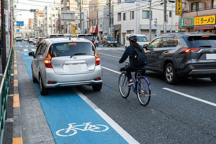 青いレーンへの駐車は場所によって違法！ 2種類の区分の違い, 駐車が違反となりやすい「自転車専用通行帯」, 「自転車ナビマーク・ナビライン」でも違反になる可能性大, 自転車レーンでの駐車違反、反則金はいくら？ 取り締まりの実態, 反則金と違反点数｜駐車違反の罰則, 駐車と停車の違い, 合法・違法を問わず危険！ 自転車レーンへの駐車が引き起こす事故リスク, 駐車車両が自転車を車道へ押し出す構造的な危険性, 予測不能な飛び出しとドアリングで加害者になるおそれ, 自転車レーン付近での安全な運転方法, 自転車の後続を走る場合：1〜1.5m以上の側方間隔を確保する, やむを得ず停車する際の安全対策：後ろを振り向く開け方「ダッチリーチ」と早めのハザード点灯, まとめ：青いレーンでの駐車回避と自転車の急な膨らみへの備えが安全の鍵, おさらい：青いレーンに関する重要ポイント