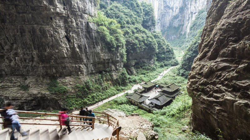 Xiaozhai Tiankeng is enormous—over 600 metres long and up to 662 metres deep. It’s so huge, the Empire State Building could fit inside—with space left over. A 2,800-step staircase leads to the bottom. The descent takes 3–4 hours through mist, cliffs, and dense greenery.