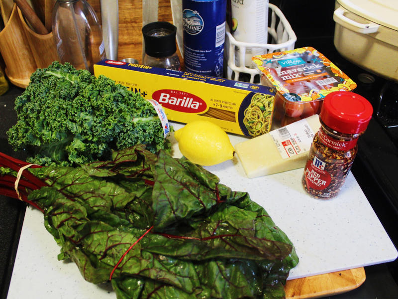 I started by gathering the ingredients for the one-pot pasta. I started by gathering the ingredients for the one-pot pasta., I chopped the tomatoes in half and added them to my skillet., I then added about a box of spaghetti to the pan., While the pasta was cooking, I chopped the Swiss chard.