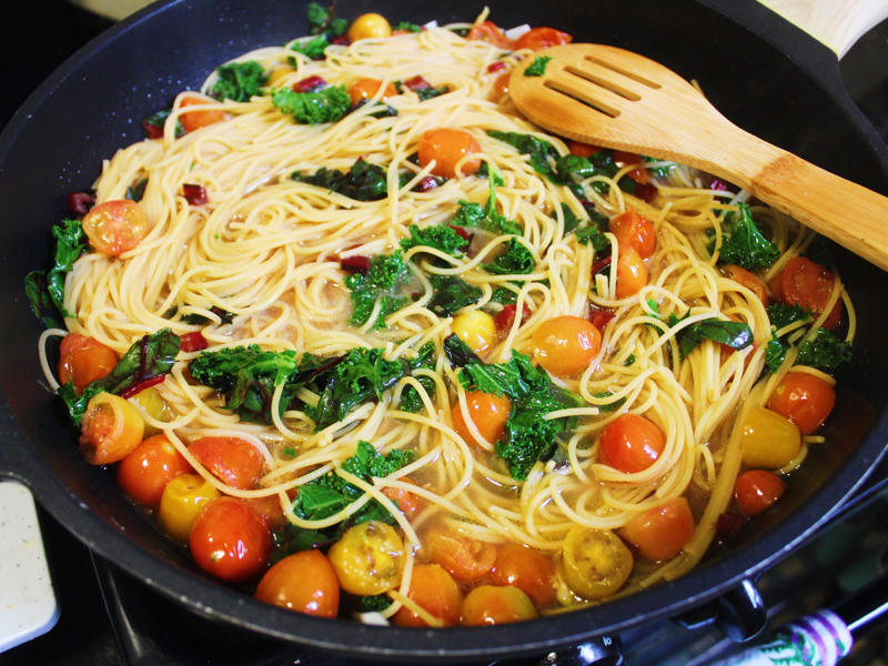 I mixed the pasta with the greens and let it cook for a few more minutes on low heat. I started by gathering the ingredients for the one-pot pasta., I chopped the tomatoes in half and added them to my skillet., I then added about a box of spaghetti to the pan., While the pasta was cooking, I chopped the Swiss chard.