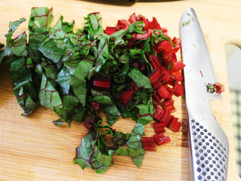 While the pasta was cooking, I chopped the Swiss chard. I started by gathering the ingredients for the one-pot pasta., I chopped the tomatoes in half and added them to my skillet., I then added about a box of spaghetti to the pan., While the pasta was cooking, I chopped the Swiss chard.
