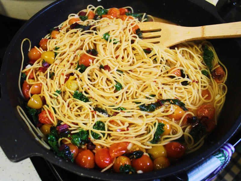 After I added the grated Parmigiano Reggiano, the sauce started to come together. I started by gathering the ingredients for the one-pot pasta., I chopped the tomatoes in half and added them to my skillet., I then added about a box of spaghetti to the pan., While the pasta was cooking, I chopped the Swiss chard.