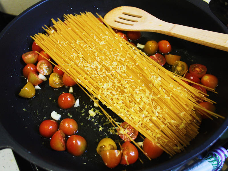 I then added about a box of spaghetti to the pan. I started by gathering the ingredients for the one-pot pasta., I chopped the tomatoes in half and added them to my skillet., I then added about a box of spaghetti to the pan., While the pasta was cooking, I chopped the Swiss chard.