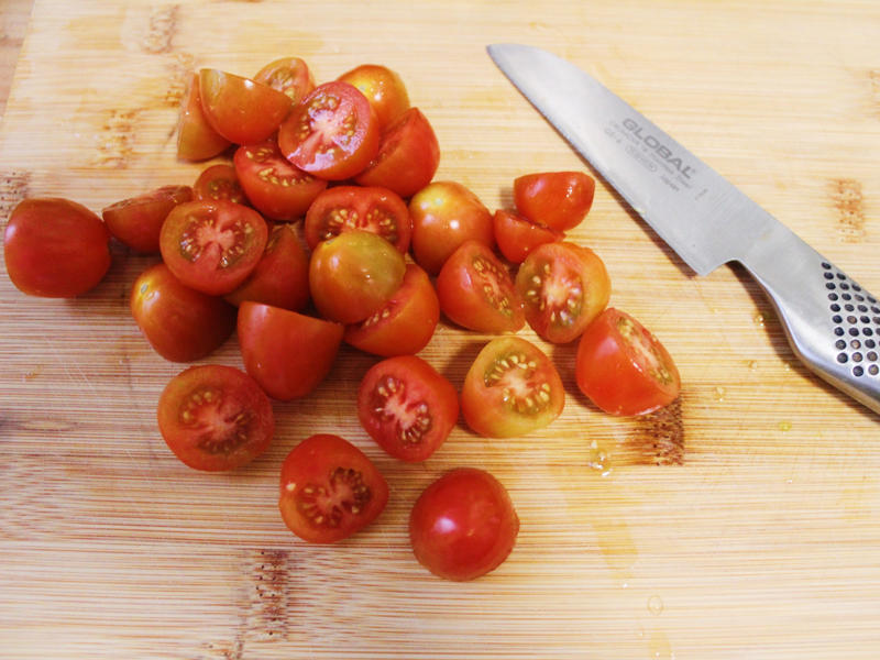 I chopped the tomatoes in half and added them to my skillet. I started by gathering the ingredients for the one-pot pasta., I chopped the tomatoes in half and added them to my skillet., I then added about a box of spaghetti to the pan., While the pasta was cooking, I chopped the Swiss chard.