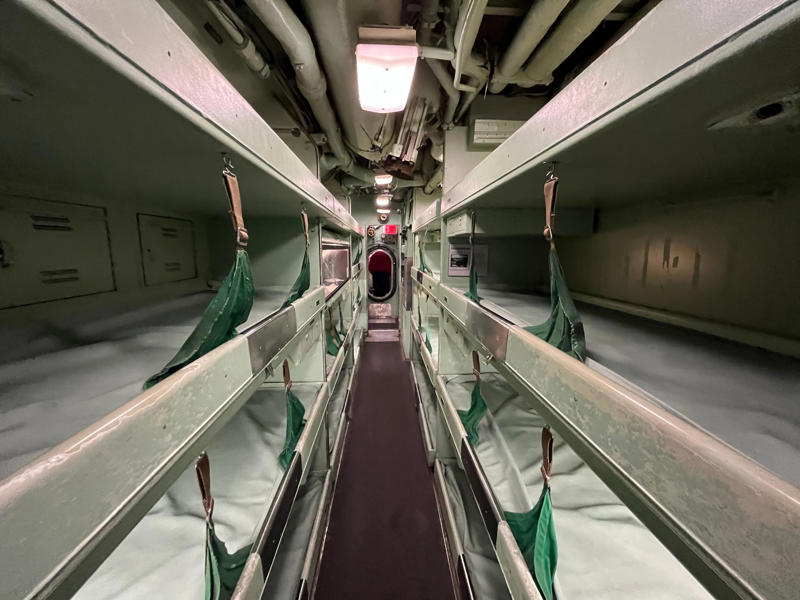 Growler's largest sleeping area contained 46 bunks. In the navigation compartment, crew members plotted courses and tracked Growler's position., The missile checkout and guidance center was once a top-secret area., Officers had access to their own shower., Officers used the wardroom to eat, socialize, and hold meetings., Yeomen handled clerical and administrative work aboard the USS Growler's tiny office., Here, the commanding officer would give orders to the crew., The sonar room also aided Growler's navigation., Crew members communicated with other ships in the radio room., Meals were prepared in the galley., In the scullery, Growler crew members washed dishes and compacted trash., The crew's mess was the only common space on the USS Growler., Growler's largest sleeping area contained 46 bunks., The crew's washroom featured two showers., Growler's three diesel engines were located in the engine room.