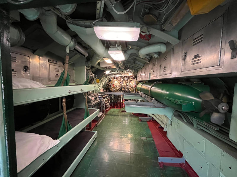In addition to carrying nuclear missiles, the USS Growler was also armed with torpedoes. In the navigation compartment, crew members plotted courses and tracked Growler's position., The missile checkout and guidance center was once a top-secret area., Officers had access to their own shower., Officers used the wardroom to eat, socialize, and hold meetings., Yeomen handled clerical and administrative work aboard the USS Growler's tiny office., Here, the commanding officer would give orders to the crew., The sonar room also aided Growler's navigation., Crew members communicated with other ships in the radio room., Meals were prepared in the galley., In the scullery, Growler crew members washed dishes and compacted trash., The crew's mess was the only common space on the USS Growler., Growler's largest sleeping area contained 46 bunks., The crew's washroom featured two showers., Growler's three diesel engines were located in the engine room.
