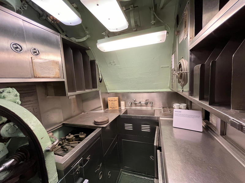 In the scullery, Growler crew members washed dishes and compacted trash. In the navigation compartment, crew members plotted courses and tracked Growler's position., The missile checkout and guidance center was once a top-secret area., Officers had access to their own shower., Officers used the wardroom to eat, socialize, and hold meetings., Yeomen handled clerical and administrative work aboard the USS Growler's tiny office., Here, the commanding officer would give orders to the crew., The sonar room also aided Growler's navigation., Crew members communicated with other ships in the radio room., Meals were prepared in the galley., In the scullery, Growler crew members washed dishes and compacted trash., The crew's mess was the only common space on the USS Growler., Growler's largest sleeping area contained 46 bunks., The crew's washroom featured two showers., Growler's three diesel engines were located in the engine room.