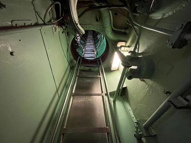 A ladder in the bridge trunk led to the bridge of the submarine. In the navigation compartment, crew members plotted courses and tracked Growler's position., The missile checkout and guidance center was once a top-secret area., Officers had access to their own shower., Officers used the wardroom to eat, socialize, and hold meetings., Yeomen handled clerical and administrative work aboard the USS Growler's tiny office., Here, the commanding officer would give orders to the crew., The sonar room also aided Growler's navigation., Crew members communicated with other ships in the radio room., Meals were prepared in the galley., In the scullery, Growler crew members washed dishes and compacted trash., The crew's mess was the only common space on the USS Growler., Growler's largest sleeping area contained 46 bunks., The crew's washroom featured two showers., Growler's three diesel engines were located in the engine room.