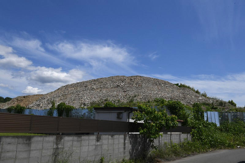2階建て建物の屋根よりも高く積み上がった産廃物＝京都市伏見区で2026年6月10日、久保聡撮影, まるで山のように積み上がる産業廃棄物＝京都市伏見区で2026年6月10日、久保聡撮影, 積み上がった産廃物。コンクリ片なども混じっている＝京都市伏見区で2026年6月10日、久保聡撮影, 積み上がった産廃物。崩れそうになっている場所も＝京都市伏見区で2026年6月10日、久保聡撮影, 積み上がった産業廃棄物。すぐ近くには民間の建物も＝京都市伏見区で2026年6月10日、久保聡撮影, 山のように積み上がった産廃物＝京都市伏見区で2026年6月10日、久保聡撮影