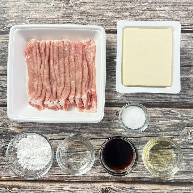 肉巻き豆腐の照り焼き, 作り方： ① 木綿豆腐はキッチンペーパーで包み、耐熱皿にのせて600Wの電子レンジで3分加熱して水切りする。粗熱が取れたら、半分の厚さに切り重ねたまま横に置き更に5等分の幅に切る。, ② バットに片栗粉を入れて①をまぶしたら、1本ずつ豚ロース肉で巻く。, ③ フライパンにサラダ油（分量外、大さじ1程度）を引き、中火で熱する。②を並べて全体的にこんがりと焼き色をつける。, ④ 合わせた【A】を加えて煮からめたら、完成！, 濃いめの味付けだからメイン料理にもオススメ◎