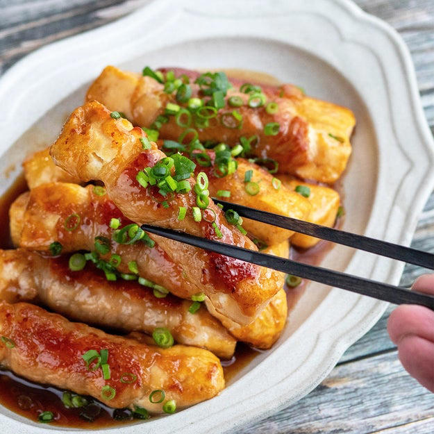 肉巻き豆腐の照り焼き, 作り方： ① 木綿豆腐はキッチンペーパーで包み、耐熱皿にのせて600Wの電子レンジで3分加熱して水切りする。粗熱が取れたら、半分の厚さに切り重ねたまま横に置き更に5等分の幅に切る。, ② バットに片栗粉を入れて①をまぶしたら、1本ずつ豚ロース肉で巻く。, ③ フライパンにサラダ油（分量外、大さじ1程度）を引き、中火で熱する。②を並べて全体的にこんがりと焼き色をつける。, ④ 合わせた【A】を加えて煮からめたら、完成！, 濃いめの味付けだからメイン料理にもオススメ◎