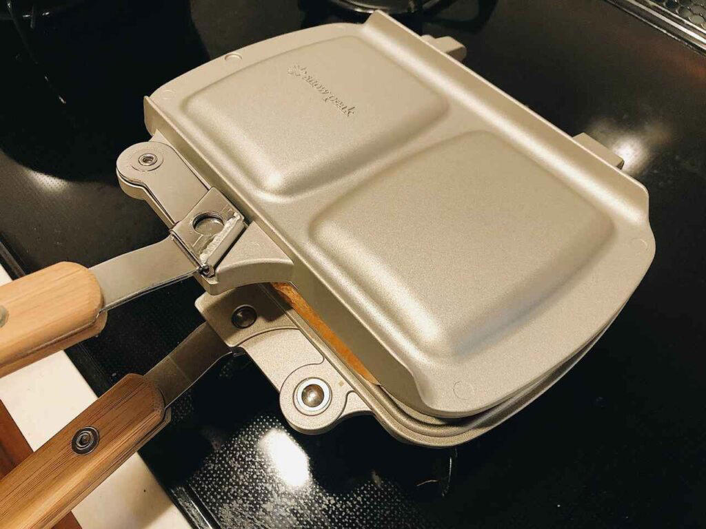 直火式ホットサンドメーカーの魅力｜電気式との違いとキャンプで選ぶべき理由, なぜ直火式がキャンプに最適なのか, 電気式との違い｜メリット・デメリット比較, 直火式ホットサンドメーカーの選び方｜失敗しない5つのポイント, ①形状で選ぶ｜シングルとダブルの違い, ②素材で選ぶ｜鉄・アルミ・ステンレスの特徴比較, ③分離式 vs 一体式｜2枚のフライパンとしても使えるか, ④家庭のIHコンロでも使いたい｜IHコンロ対応モデルを検討する, ⑤耳まで焼ける vs 耳を切るタイプ｜好みで選ぶ, 【総合ランキング】直火式ホットサンドメーカーおすすめTOP3, 1位：バウルー サンドイッチトースター ダブル XBW02, 2位：TSBBQ ホットサンドメーカー TSBBQ-004, 3位：コールマン ホットサンドイッチクッカー 1709435, 【用途・素材別】直火式ホットサンドメーカーおすすめ7選, キャンプ専用派向け｜軽量・コンパクトモデル2選, 家庭兼用派向け｜IH対応・分離式モデル3選, 本格派向け｜鉄製・蓄熱性重視モデル2選, 直火式ホットサンドメーカーの使い方とお手入れ方法, 基本的な焼き方｜失敗しない火加減のコツ, お手入れ方法｜焦げ付き防止とシーズニング, まとめ｜直火式ホットサンドメーカーでキャンプ飯を楽しもう！