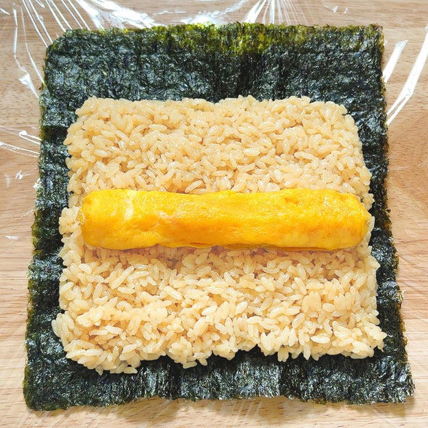作り方：① 炊飯釜に【A】を入れ、２合の目盛りまで水（分量外、適量）を注いで炊飯する。, ② 卵焼き器にサラダ油を半量引いて中火に熱し、混ぜ合わせた【B】を流し入れて全体に広げる。表面が半熟状になるまで焼き、奥から手前に巻く。同様にもう1つ作る。, ③ 焼きのり1枚をラップの上にのせる。上部3cmほどを残して①の半量を全体に広げ、②をのせて巻く。同様にもう1本作る。ぬらした包丁で食べやすい大きさに切ったら、完成！, おにぎりよりこっちがいい！！