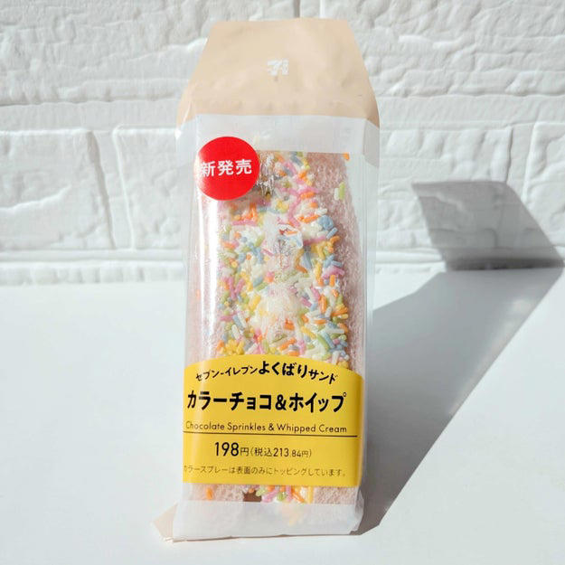 Xで話題になっている、セブンの“あるスイーツ”を買ってみました！, チョコスプレーがふんだんにトッピングされた、欲張りなサンドイッチ！, ホイップクリームがたっぷりで分厚いんです。, カラフルなチョコスプレーがかわいい。, チョコスプレーの懐かしい味を堪能できますよ。, ホイップクリームは、さっぱりしていてクドくない。, ふわふわのパンとクリームのバランスがちょうどいい。, 子どもの頃の夢が叶う、特別感のあるサンドイッチでした。